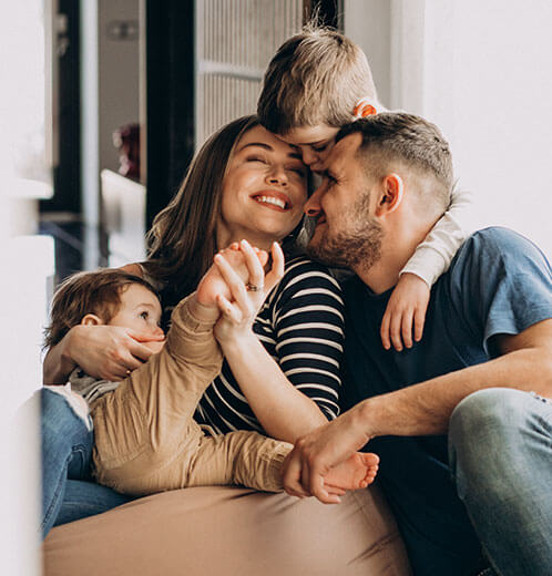 Eine Familie umarmt sich auf einem Sofa und genießt gemeinsame Zeit