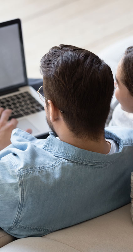 Ein Paar sitzt vor einem Laptop und informiert sich über die Schufa